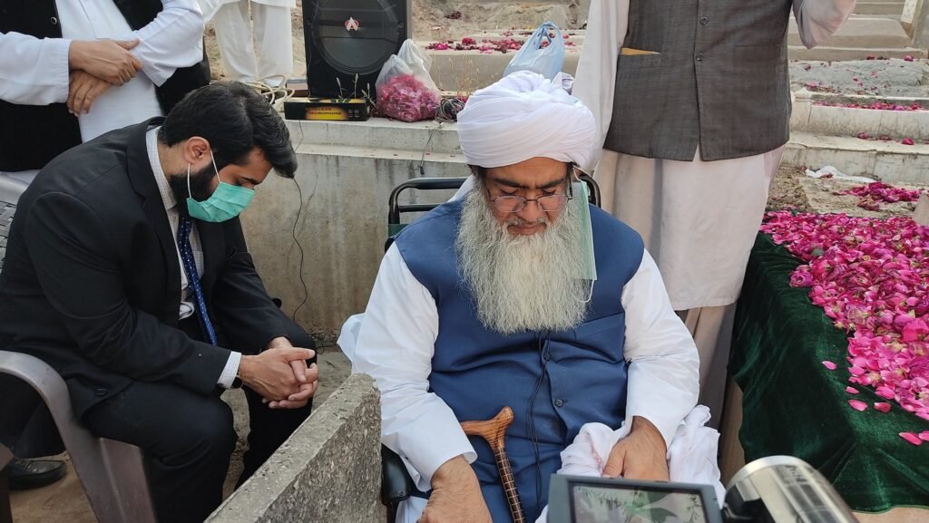 Shaykh Muhammad Bin Mohsin Mohsini and Shaykh Barrister Ahmad Mohsin Mohsini seated on formal chairs, listening to a discourse during an intimate scholarly session (Majlis) in a drawing room setting.
